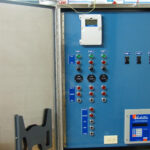 Industrial control panel with various switches, buttons, indicator lights, and meters mounted inside a metal cabinet.