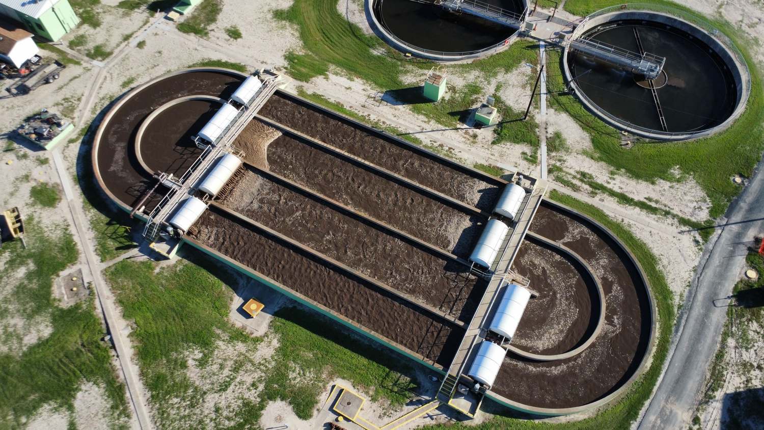 Close aerial view of an oxidation ditch with rotor aerators in operation